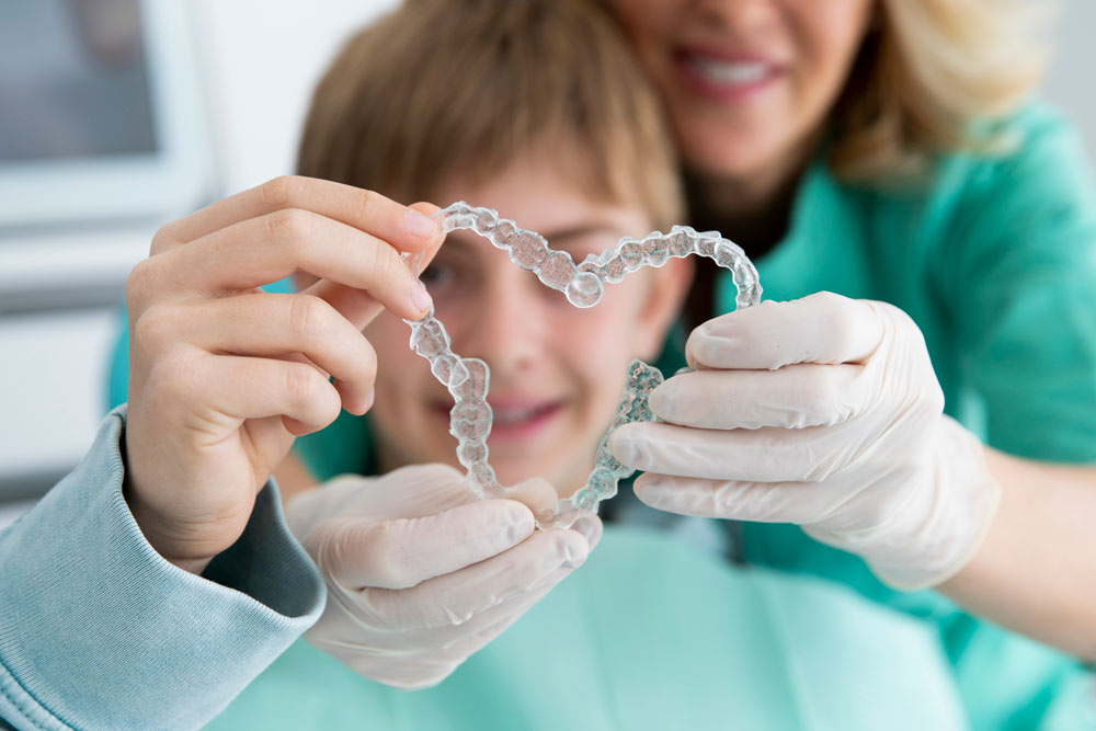 Ett barn och en tandläkare som håller i tre tandställningar som bilder ett hjärta